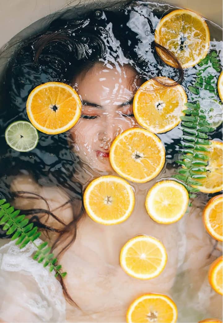 Woman Laying in Bath with Orange Slices masajes tántricos alicante